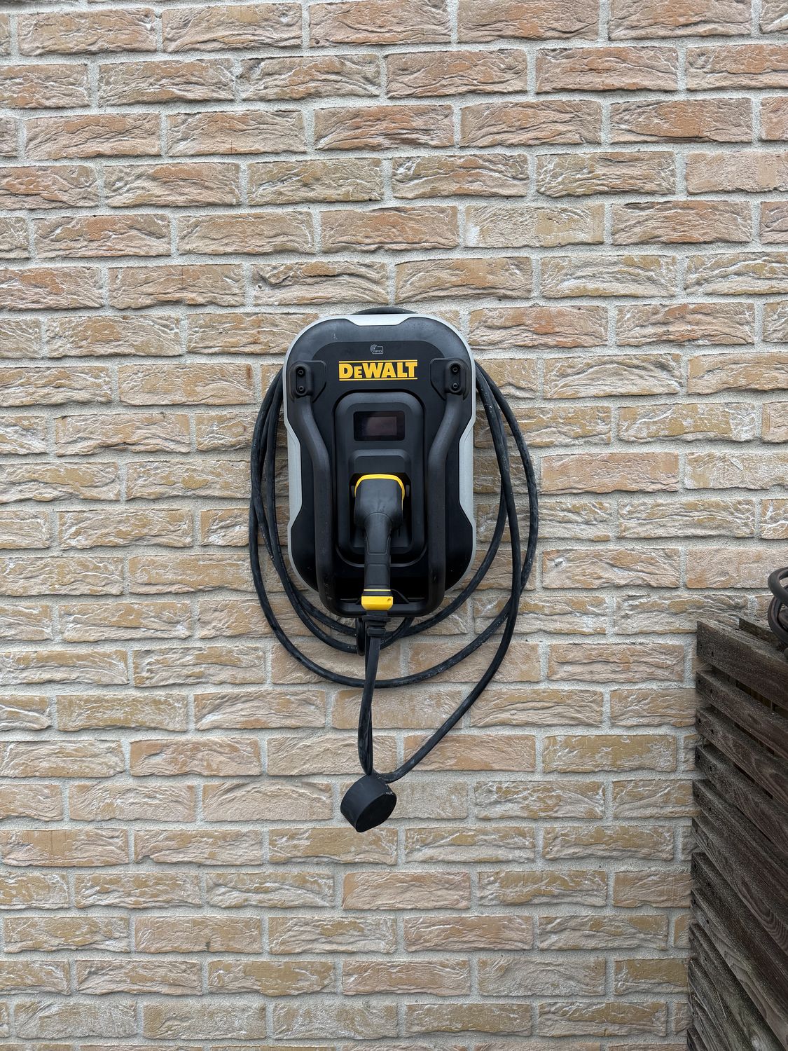 Borne de recharge murale DeWalt installée par HG'ELEC sur une façade en briques